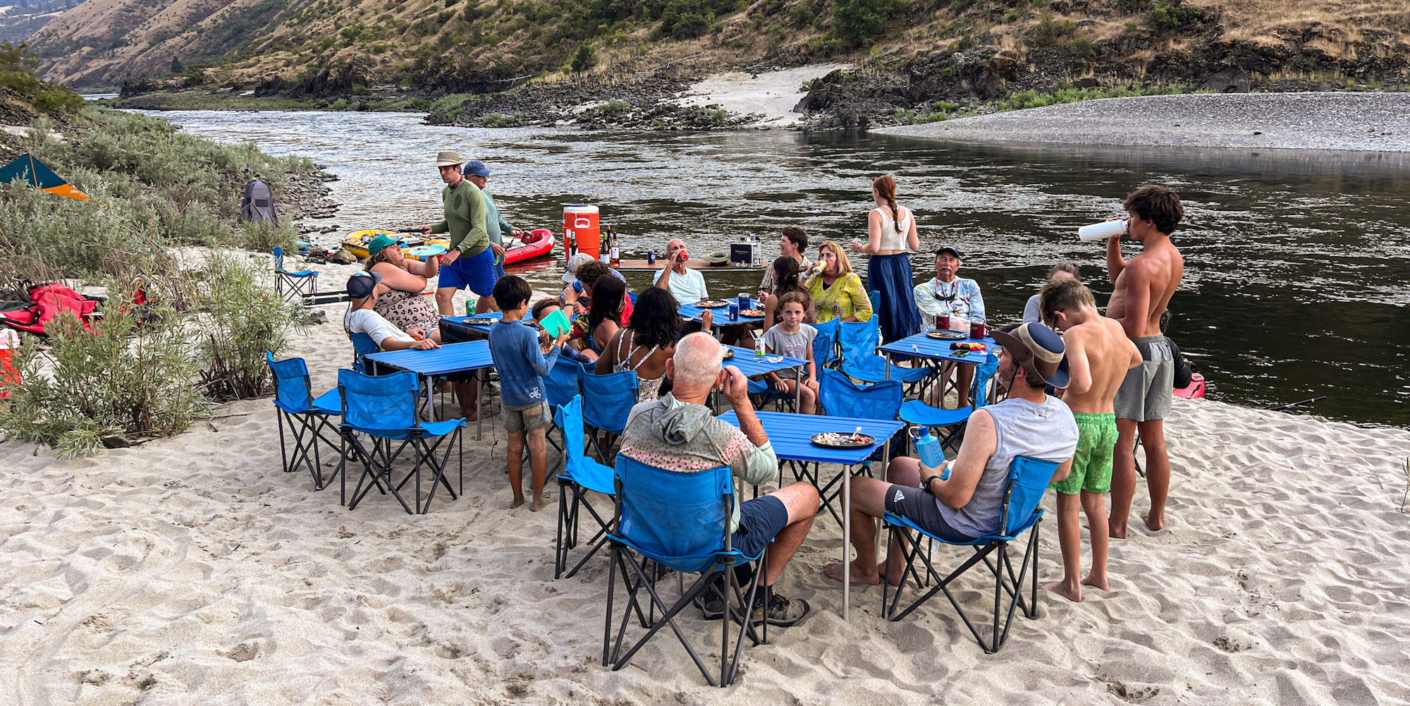 New friends gathered around square blue tables conversing along the Salmon River