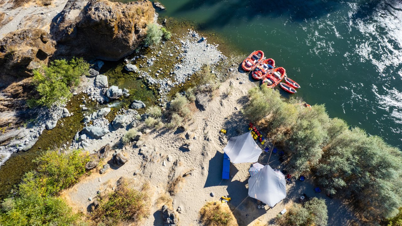 Birds eye view of a camping set up on a white sand beach next to a tributary running into the Rogue River in Oregon