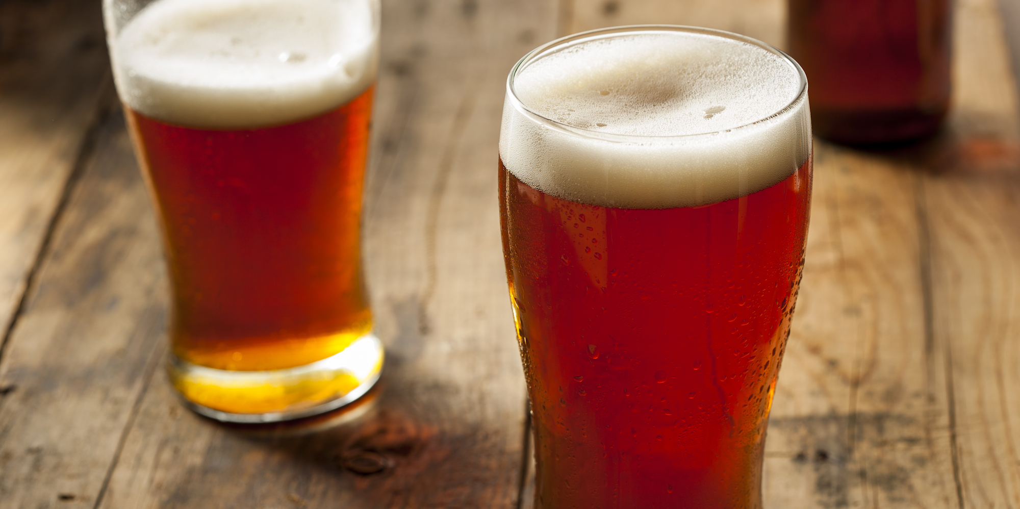 Two pints of beer on tap freshly poured with a foam top