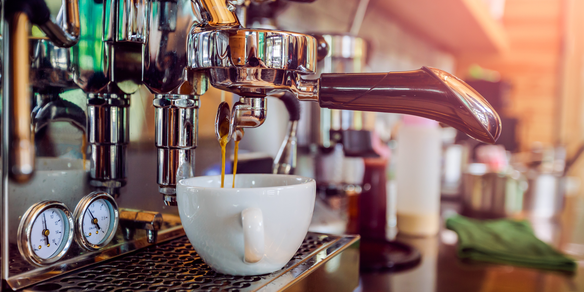 Espresso shots dripping from an industrial grade espresso machine into a white porcelain mug 