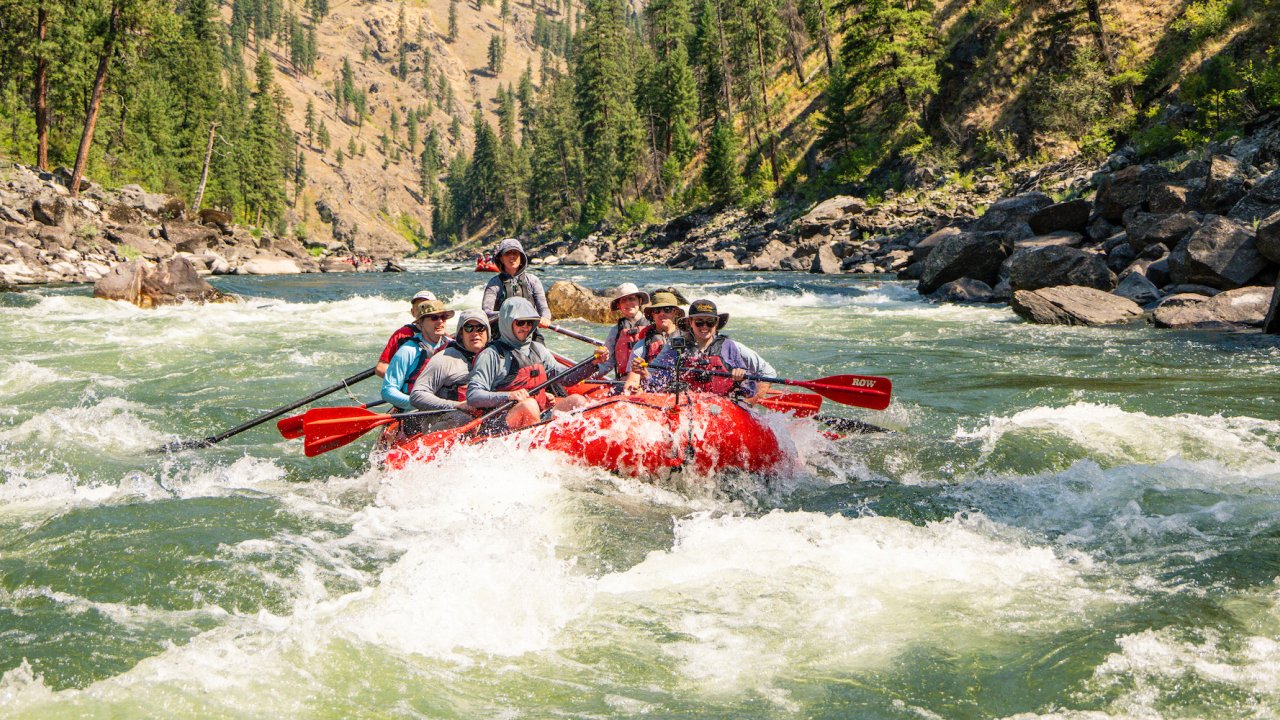 A group of people in a red paddle raft in the middle of a rapid on the Main Salmon River