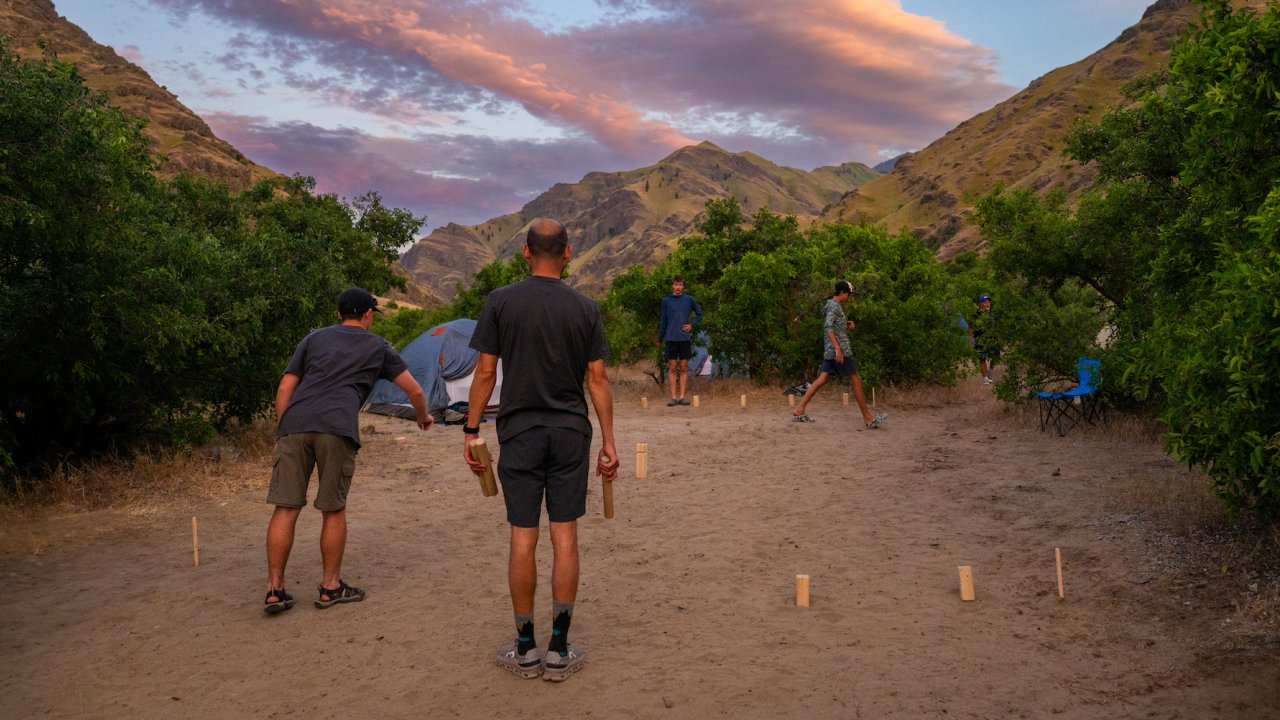 A group of campers playing horseshoe at a sandy campsite along the Snake River