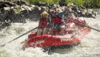 A couple on the bow of a red raft as a guide rows them through a rapid on the Rogue River