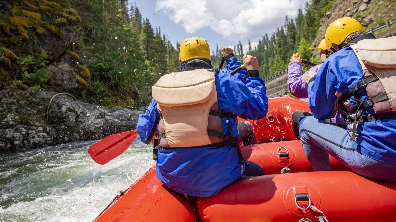 Picture from the back of the boat of paddlers on a red raft entering a rapid
