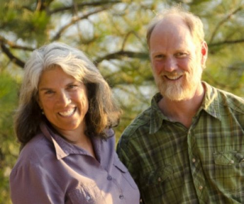 smiling couple with trees in the background