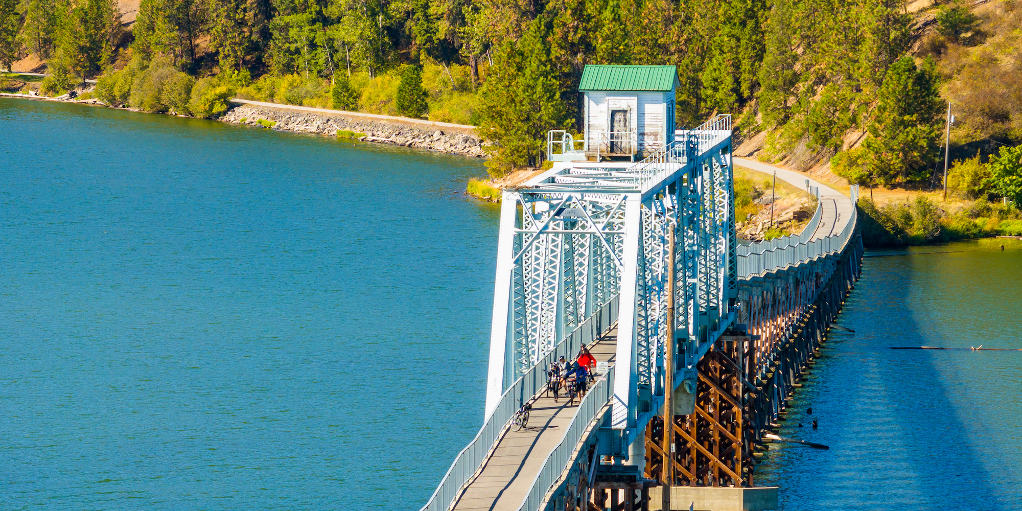 People on e-bikes biking across the Chatcolet Bridge in Idaho