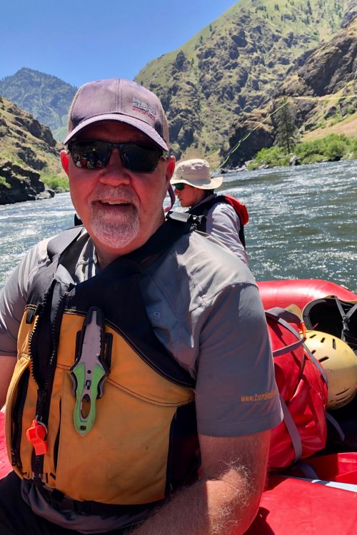 man in yellow pfd on red whitewater raft