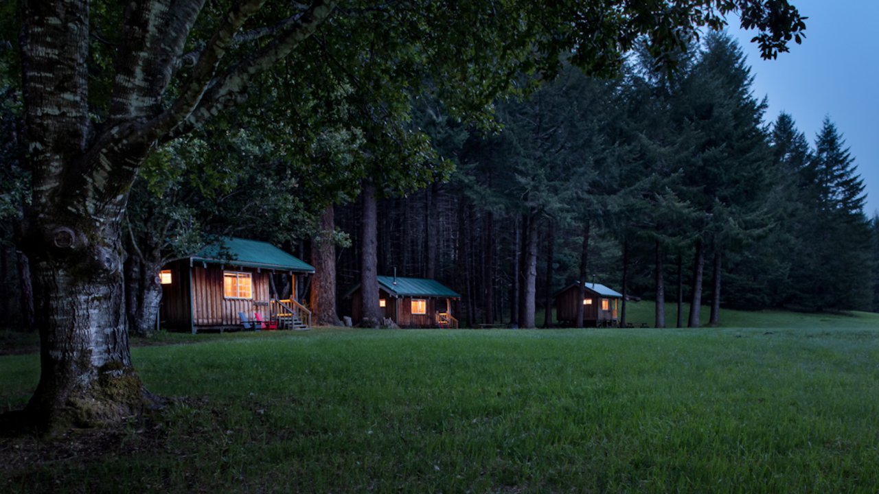 A row of cabins in a green field surrounded by trees in the Rogue River Wilderness in Oregon