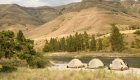 Tents set up on a sandy riverbank surrounded by Idaho hills.