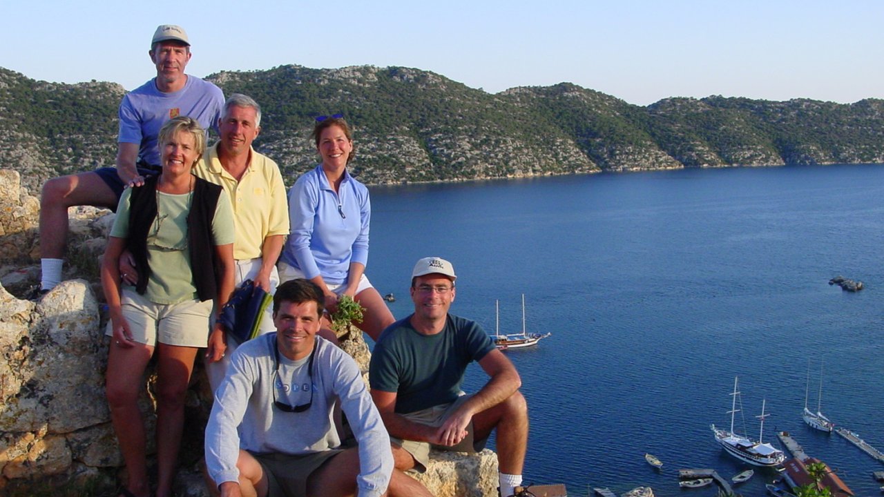 A group of people on a ocean overlook hike smiling together for a photo at sunset