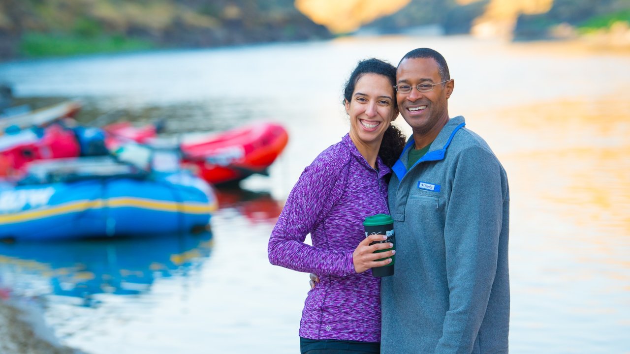 Couple smiling on the beach beside rafts during a Lower Salmon River rafting trip through the scenic Salmon River canyons in Idaho.