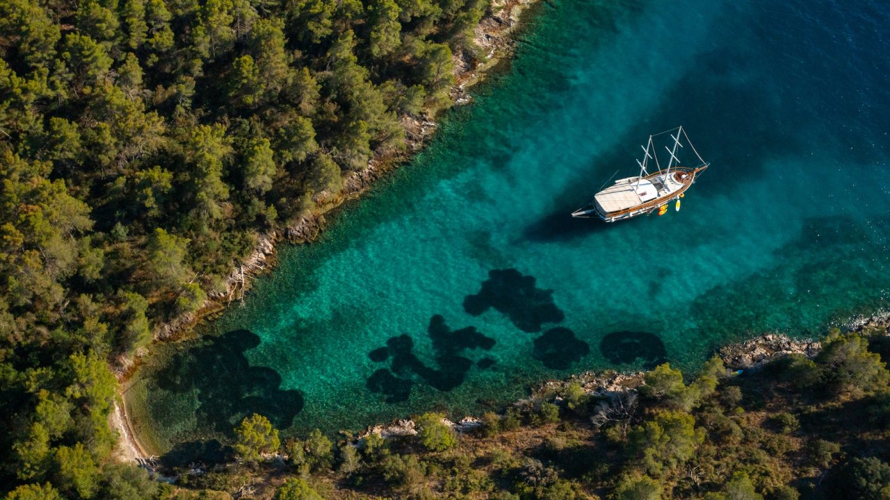 An areal view of a yacht anchored in a secluded cove along the Croatian coastline.