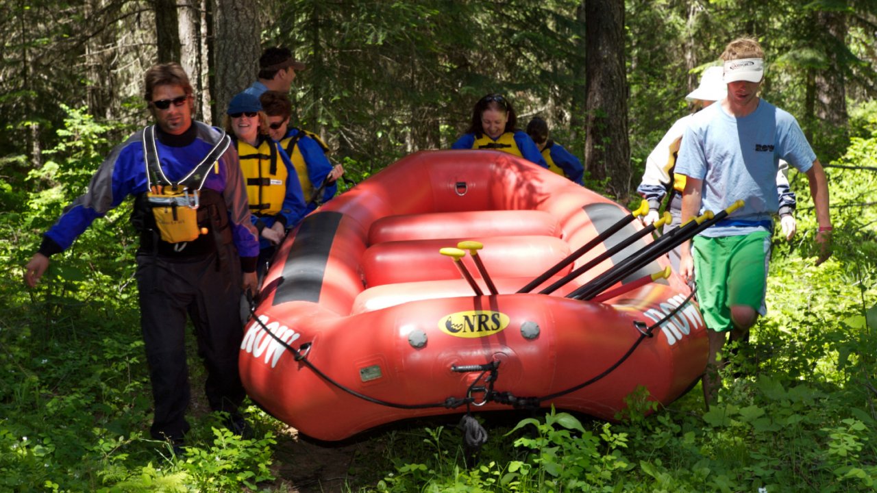 people portaging a raft in the woods