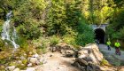 Cyclists exiting a tunnel beside a waterfall on the Route of the Hiawatha biking trail