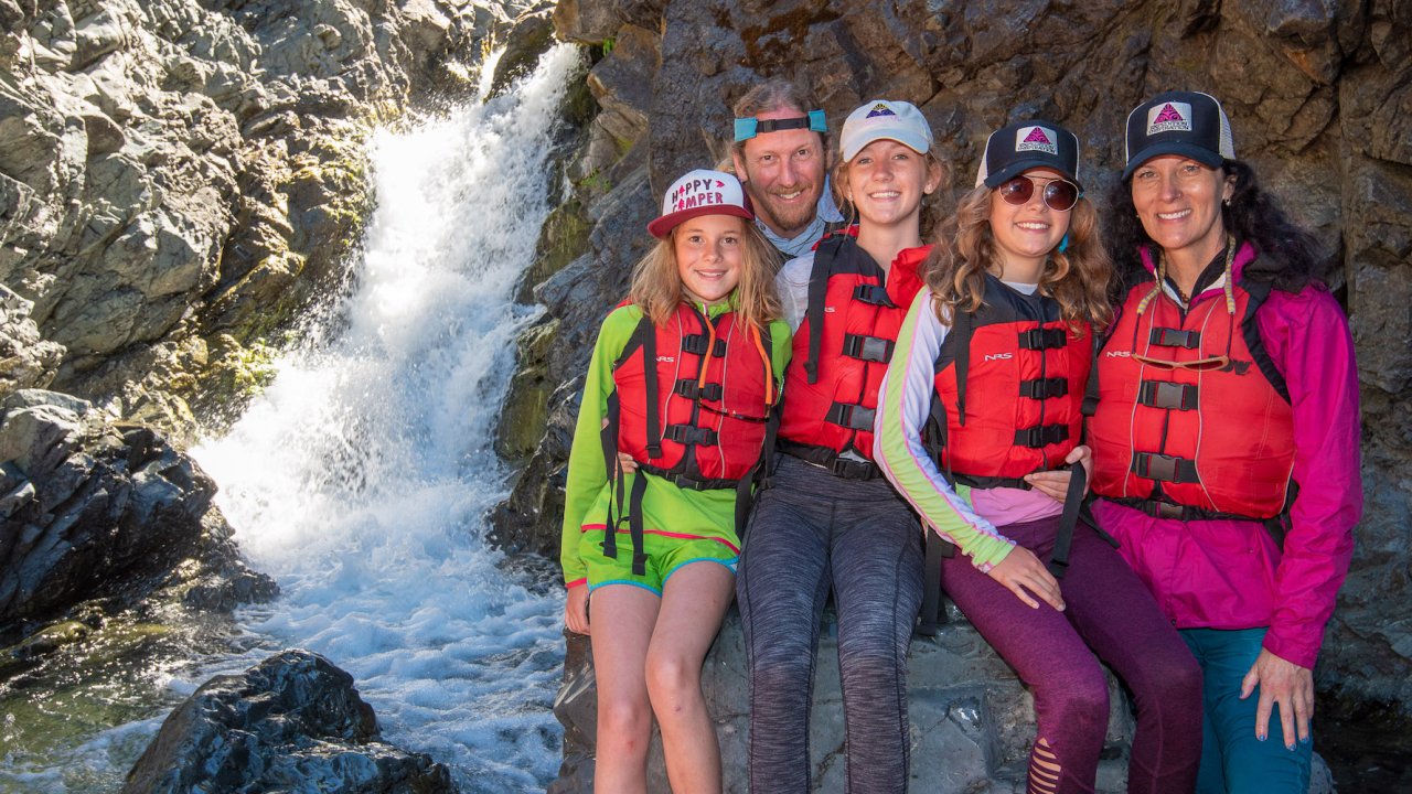A family standing and smiling next to a waterfall in Oregon