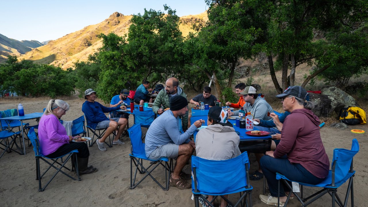 People sitting around a table eating dinner on a multi-day Snake River rafting trip