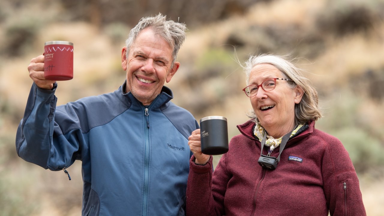 Smiling couple enjoying coffee outdoors on a relaxed family vacation surrounded by nature and desert canyon scenery