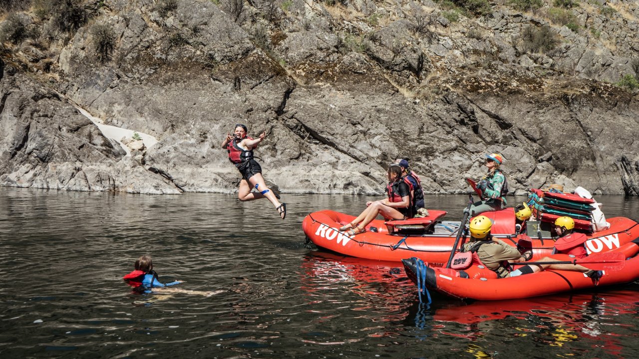 A person jumping off of a red ROW Adventures raft while on a rafting adventure in Idaho.