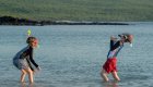 Family rafting trips with children playing in shallow river water at a sunny riverside stop during a family vacation