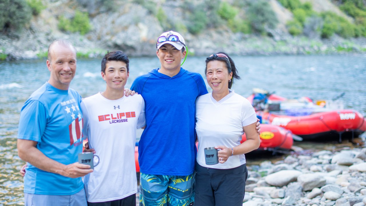 family smiling on a riverside beach while whitewater rafting in Idaho