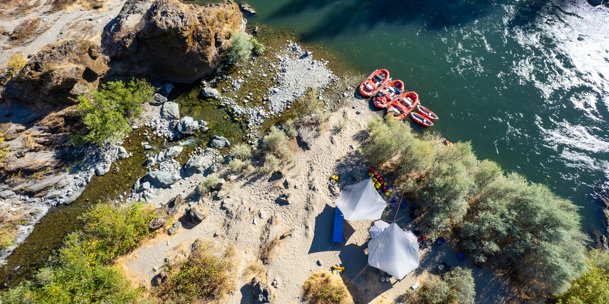 Birds eye view of two tarps set up for shade at a campsite along the Rogue River