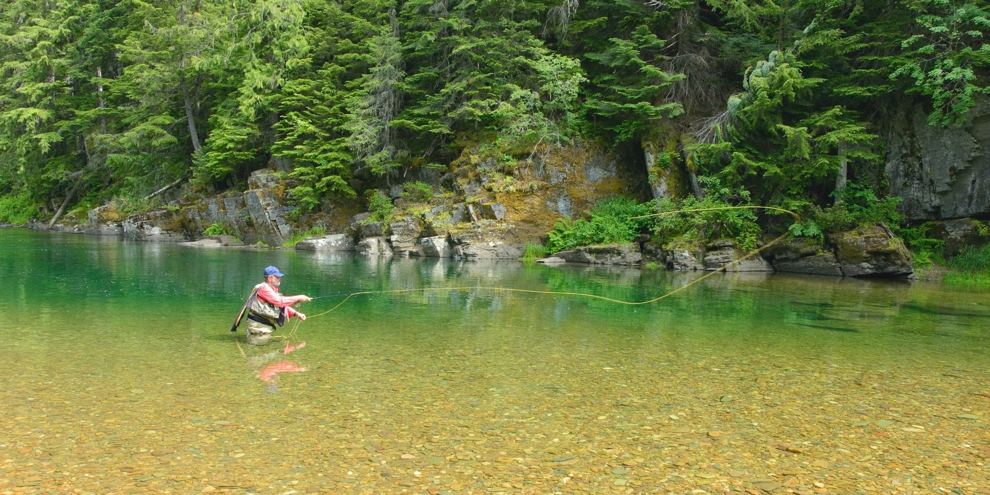A man fly fishing waist deep in the Coeur d'Alene River in Northern Idaho