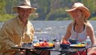 Happy anglers eating lunch on the river while on a guided fly fishing tour