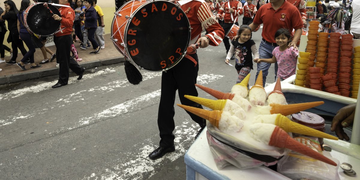 Parade through the streets of the Galapagos with two young girls in the corner admiring traditional Galapagos ice cream 