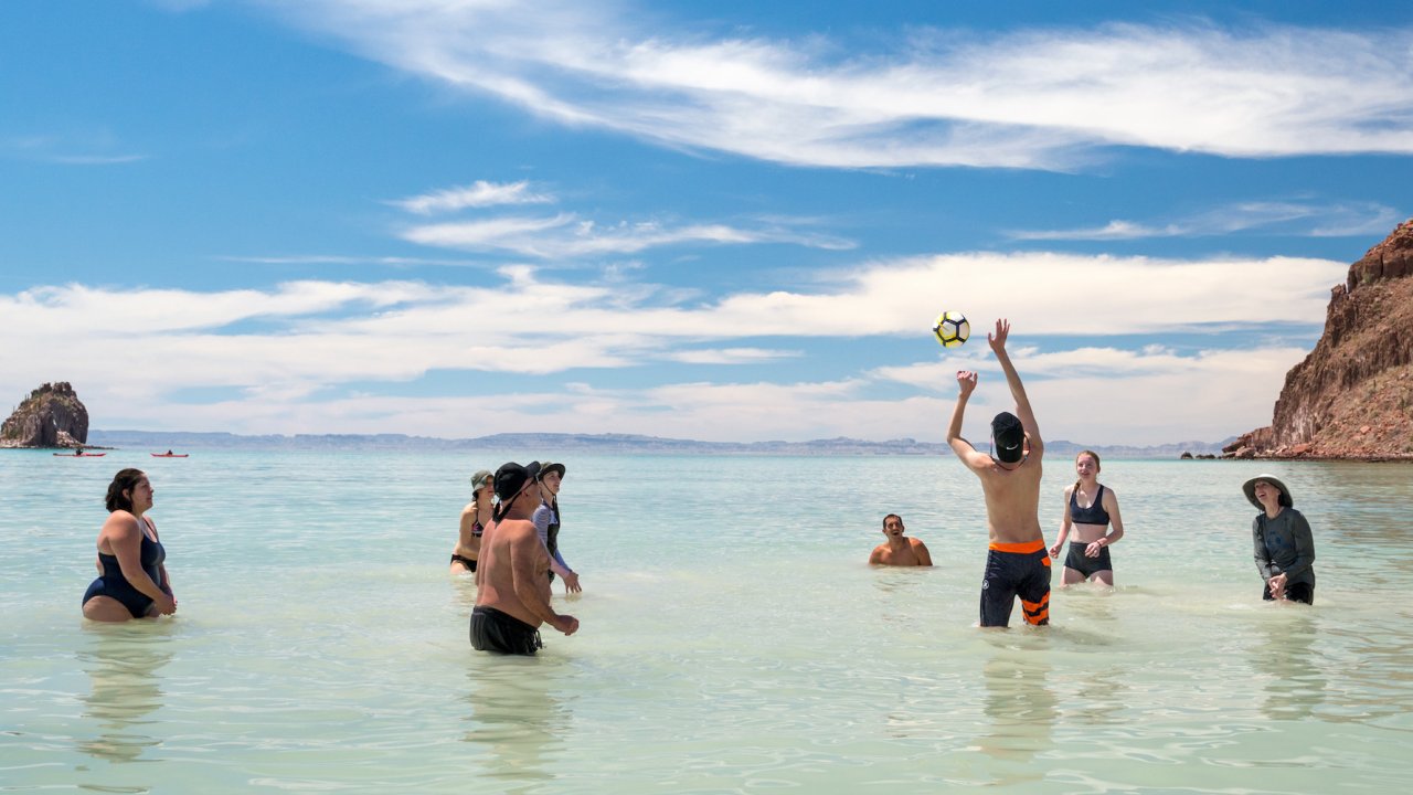 Group of guests playing an impromptu game of beach volleyball at camp