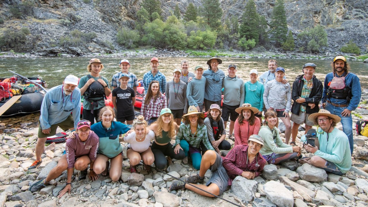 Happy rafting group posing by the Middle Fork of the Salmon River in Idaho after a multi-day whitewater adventure.