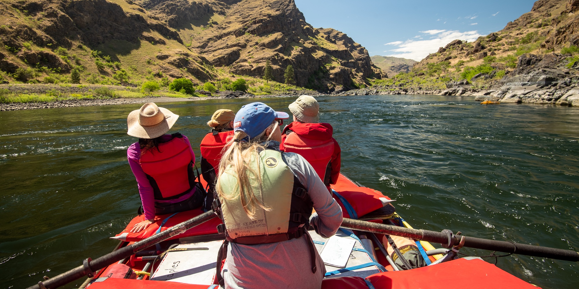 A river guide rows a raft through a calm stretch of the Snake River, offering a quiet moment of reflection and connection with the water. 