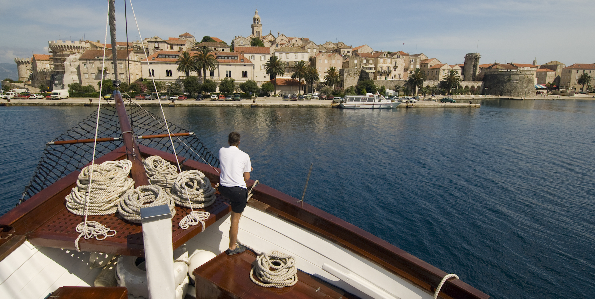 A crew member aboard a chartered Gulet standing in the bow ready to tie the boat up to a harbor