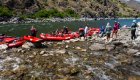 A row of red rafts along a river bank on the Snake River