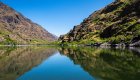 Peaceful view of the Snake River reflecting canyon walls along the Snake River Canyon Trail, a popular hike in Hells Canyon, Idaho.