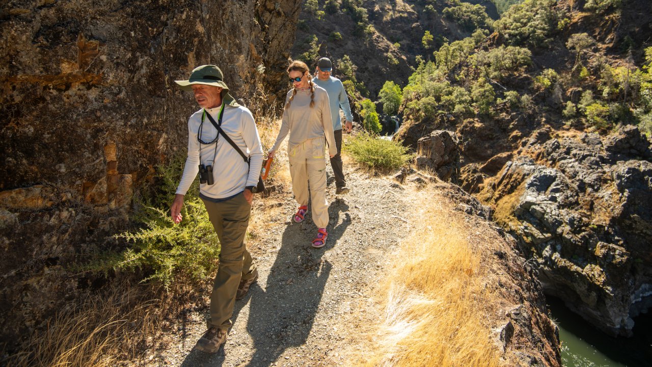 People walking along the Rogue River wilderness trail in Oregon on a sunny morning