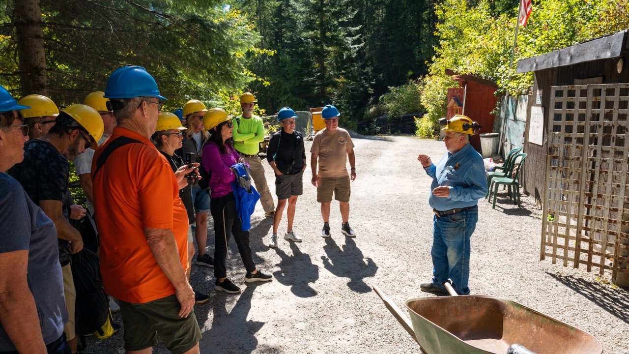 Tour group wearing helmets listens to a guide during an Idaho adventure tour with biking and history experiences.