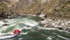 Raft navigating whitewater rapids through a rocky Idaho canyon.