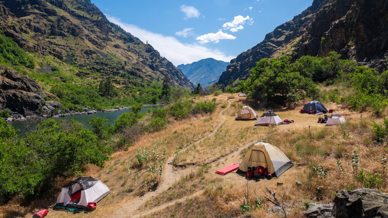 Tent campsite along the Snake River in Hells Canyon, Idaho, surrounded by rugged canyon walls and scenic river views on a whitewater rafting trip.