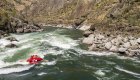 Red raft floating downstream through a rapid on the Lower Salmon River from a drone shot