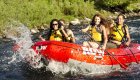 Group of friends whitewater rafting on Idaho’s Clearwater River, paddling through splashing rapids in a bright red ROW Adventures raft — thrilling Idaho rafting experience.