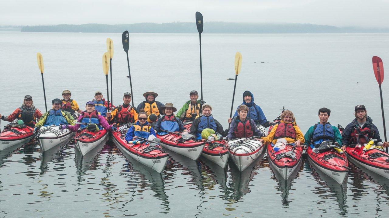 Sea kayakers with their paddles up celebrating the completions of their multi-day sea kayaking trip in British Columbia off Vancouver Island.