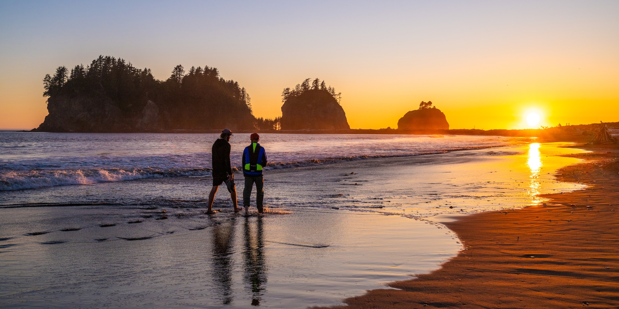 Visitors walking along La Push Beach at sunset with sea stacks in the distance on Washington’s Olympic Peninsula.