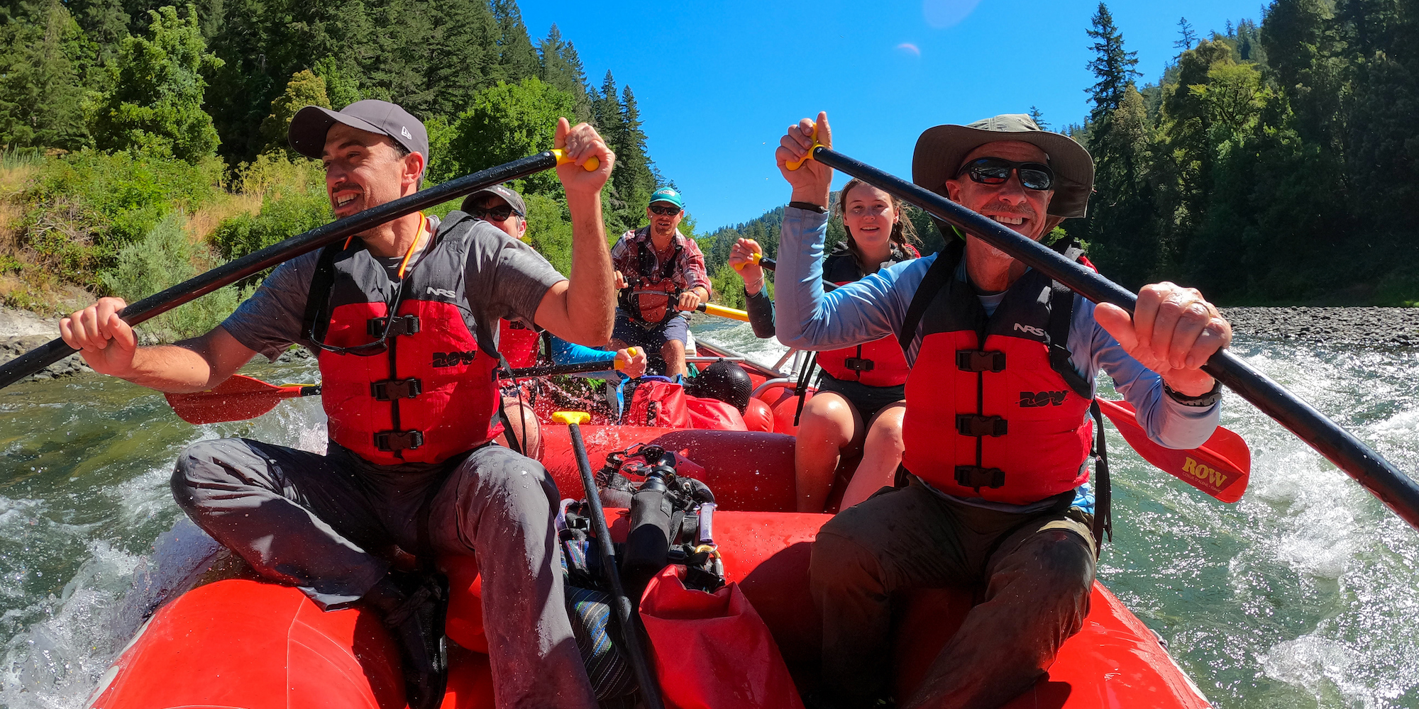 View of a group of rafters paddling downstream through a rapid
