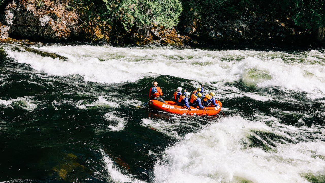 A red raft enters a rapid moving downstream on the Lochsa River