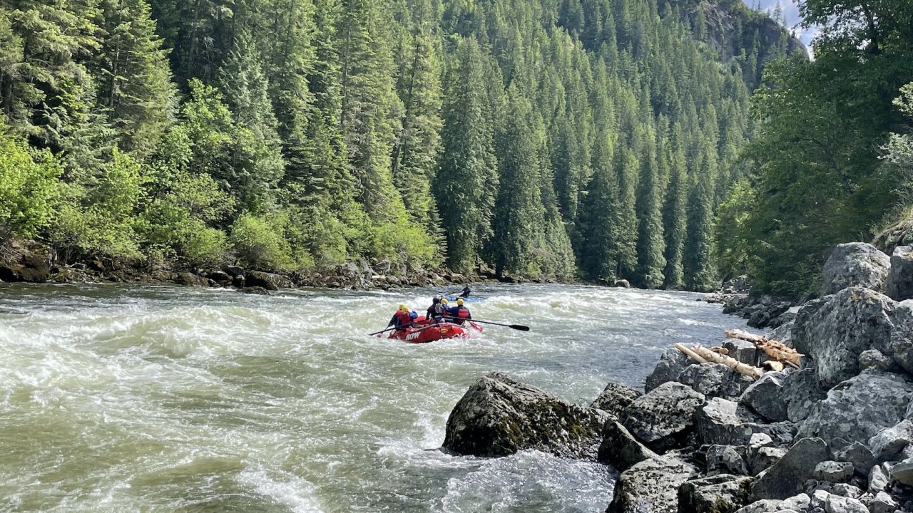 Lochsa River along with rocks on the shore while a raft in the distance moves downstream