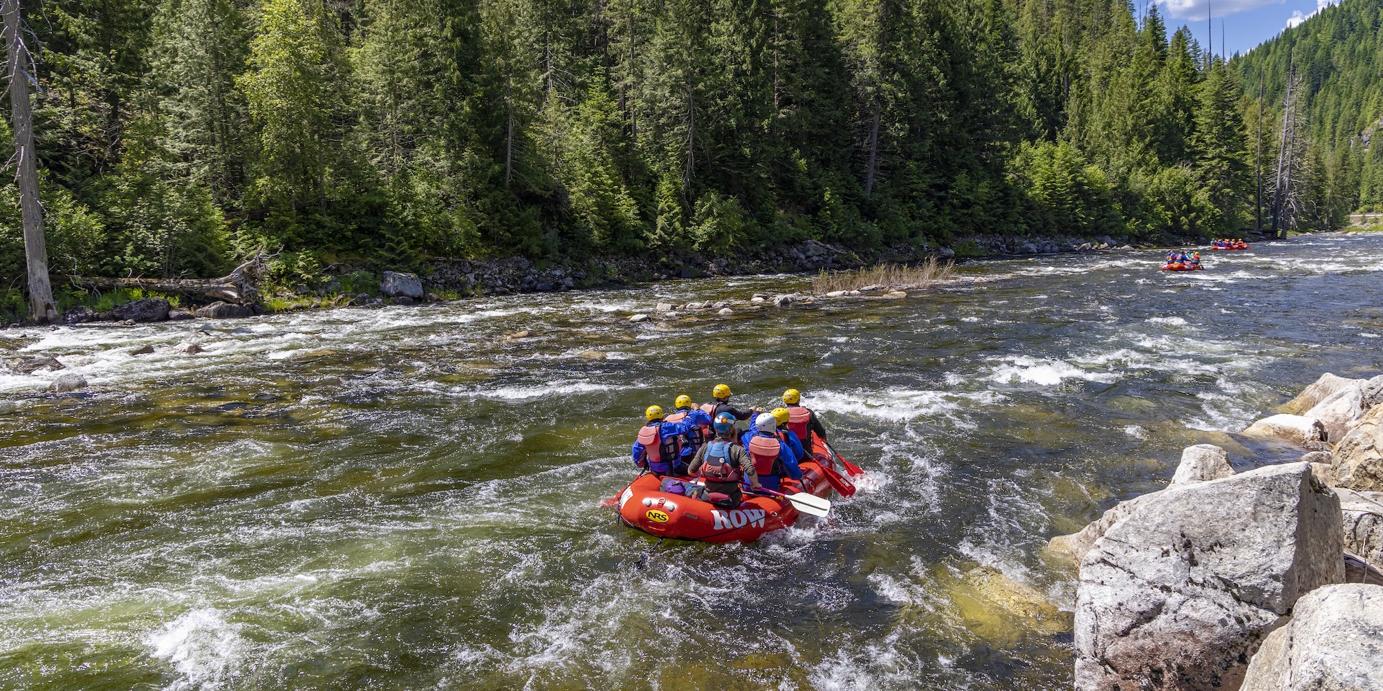 Red ROW Adventures raft floating down a clear section of the Lochsa river.