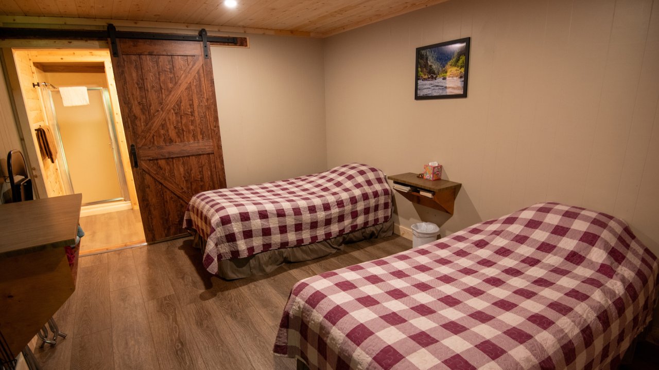 Two twin beds inside a beige room with a night stand separating the two
