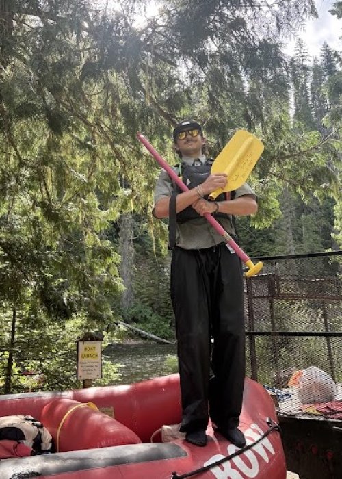ROW Adventures river guide standing on top of a red ROW raft holding a broken red and yellow paddle
