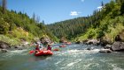 Red rafts floating downstream on the Rogue River on a sunny summer day