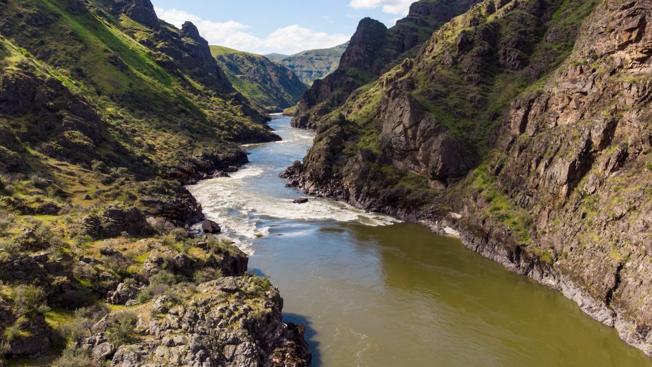 Scenic canyon view of the Rogue River in Oregon with rugged cliffs and flowing rapids, a stunning backdrop for rafting and riverside camping trips.